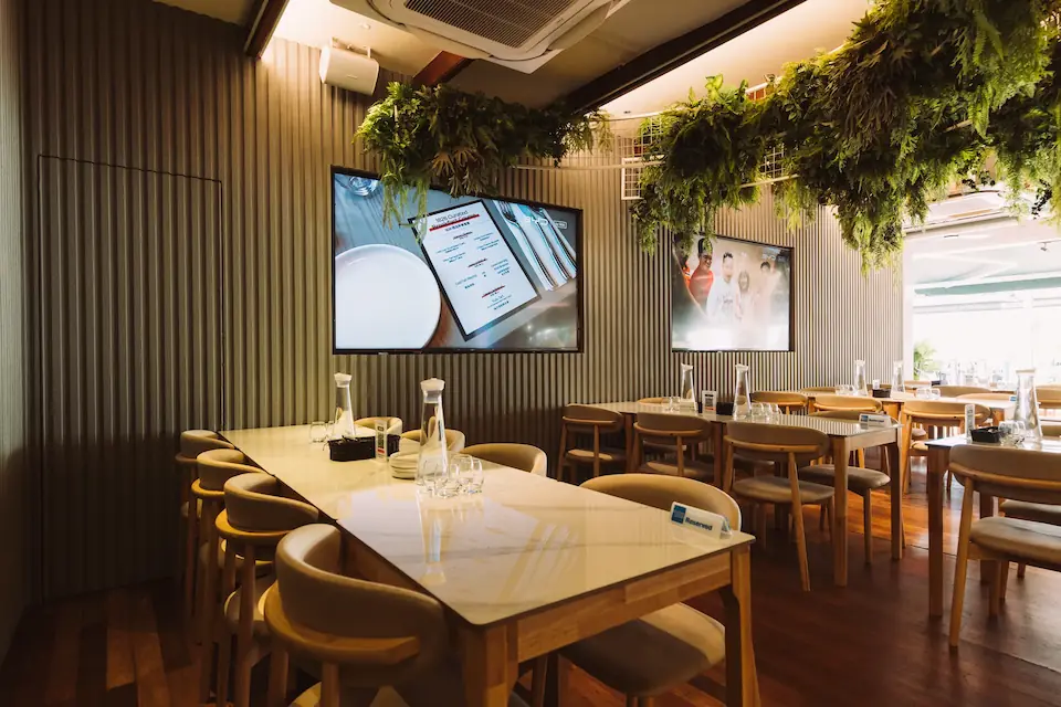 Indoor dining space with marble tables and hanging greenery at 1826 Boat Quay
