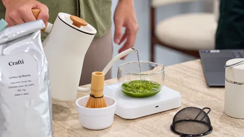 Pouring hot water into a glass bowl of matcha